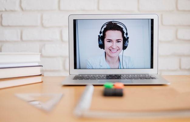 Front view of laptop on desk with female tutor holding online class Free Photo